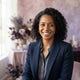 A diverse woman with a smiling expression in a professional studio portrait with soft-toned background accents.
